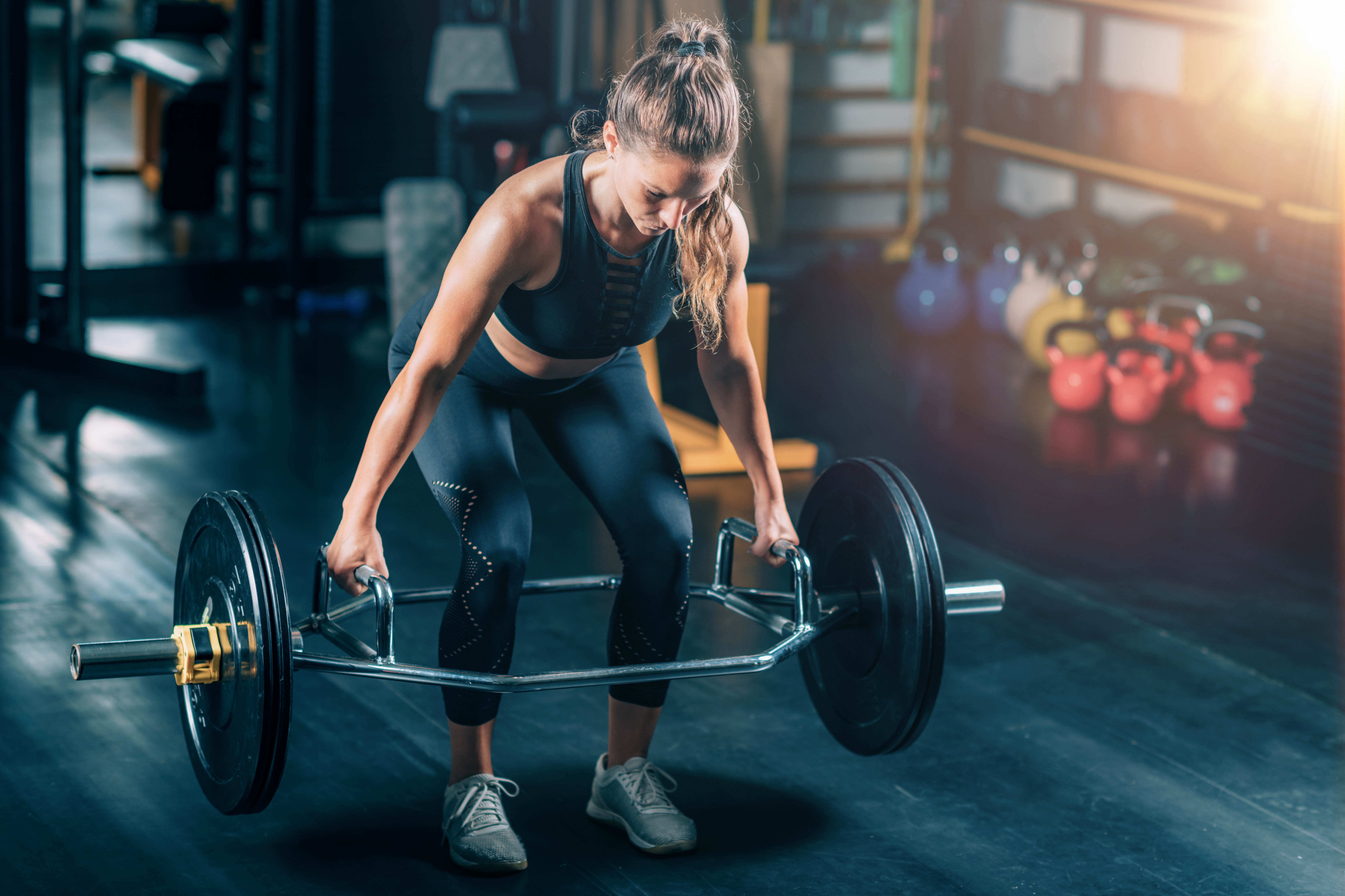 Strong woman lifting a trap bar deadlift in a gym